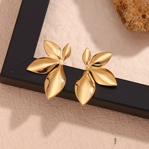 Detailed shot of 18K gold plated leaf earrings resting on a black frame with stone decor