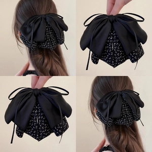 Detail showing a large layered black satin and polka dot fabric bow clip on model's hair
