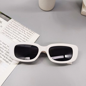 Flat lay of white narrow rectangular kids sunglasses with black UV lenses on magazine