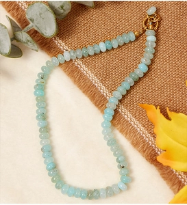 Macro detail of aquamarine crystal beaded necklace with a golden round buckle closure