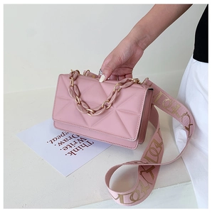Detailed close-up of pink quilted crossbody bag with stylish chain and wide strap