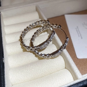 Macro detail of silver chain link hoop earrings with sparkling zircons in a jewelry box
