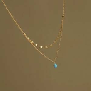 Détail d'un collier doré double épaisseur avec un pendentif goutte en opale bleue
