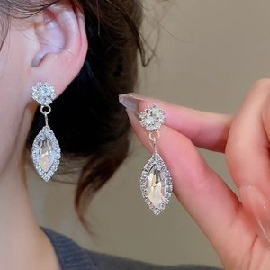 Macro shot of silver crystal water drop earrings with floral design on model