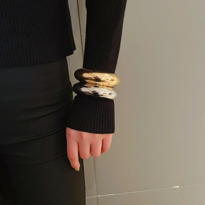 Close-up of polished gold and silver thick circular bangles worn on a wrist