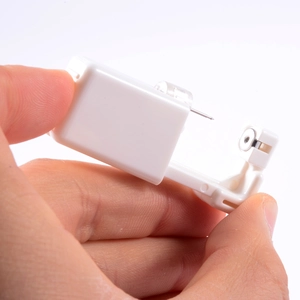 Close-up of a hand holding a sterile white disposable ear piercing gun tool