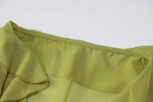 Detail of lime green chiffon blouse featuring ruffle trim and V-neckline stitching