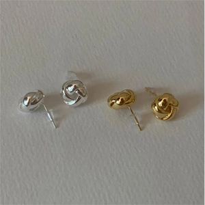 Dettaglio di orecchini a perno con nodo intrecciato in finitura oro e argento