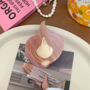 Close-up of pink onion-shaped hair claw clip on a tray with decorative props