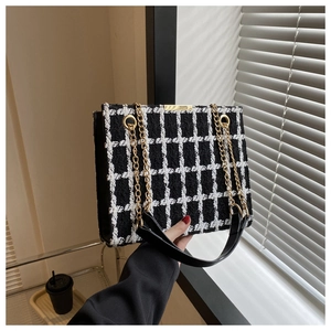 Close-up of black and white checkered tweed shoulder bag with gold chain strap detail