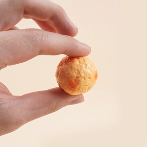 Mano che tiene un modello realistico di polpo takoyaki in miniatura in PVC