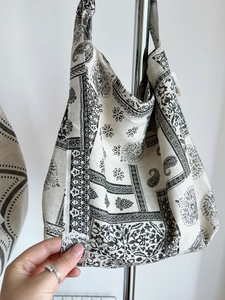Detailed texture of cotton linen fabric with black paisley print and brand logo tag