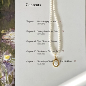 Elegant 925 silver pearl necklace with oval pendant on artistic book background
