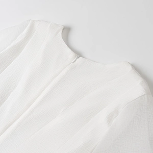 Close-up of white dress neckline with pleated chiffon texture and invisible zipper detail