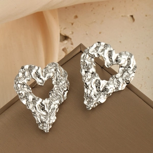 Détail de boucles d'oreilles cœur argentées avec texture sur un couvercle de boîte cadeau