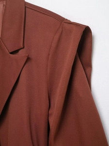 Detailed close-up of padded shoulders and reddish-brown textured fabric of a blazer