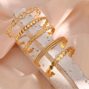 Set of five gold titanium steel open bracelets with textured woven and bead designs