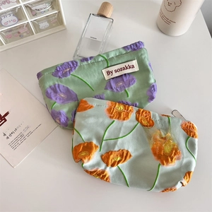 Detailed view of floral embossed fabric cosmetic pouches with zip and woven brand label