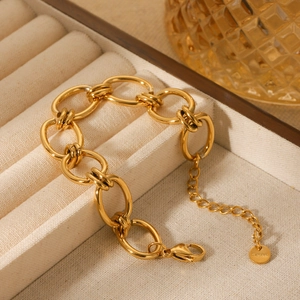 Polished gold stainless steel O-chain link bracelet on a beige velvet jewelry tray