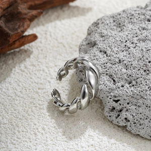 Macro detail of silver twisted chain ring on a textured stone and wood background