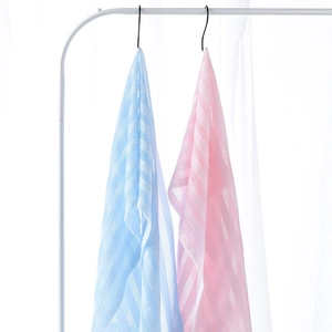Long exfoliating back scrubber towels in blue and pink stripe texture hanging on rack