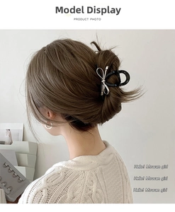 Detail of a chic black bow hair claw clip with silver edges on a model's half-up hair