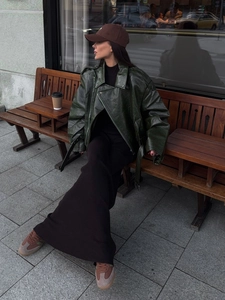 Close-up of deep green leather moto jacket styled with a long black knit dress