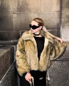 Close-up of brown faux fur short jacket with stand collar on model in outdoor setting