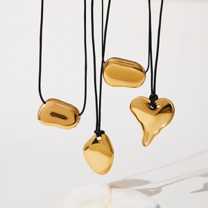Polished gold organic heart and bean pendant necklaces on black leather cord
