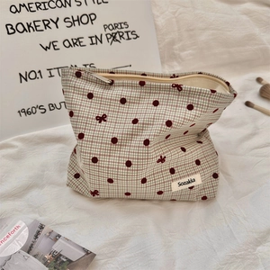 Close-up of checkered fabric makeup bag with red polka dots and bow tie pattern details