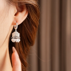 Detail of silver bell earring with hanging pearl shown on model in soft light