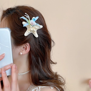 Close-up of a resin starfish hair clip with pearls worn by a model for a beach vacation look