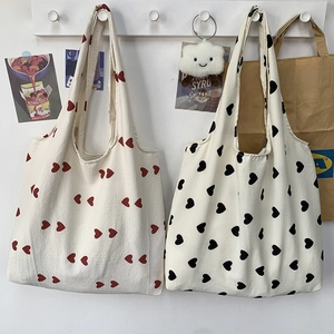 Close-up of durable canvas tote bags featuring vibrant red and black heart patterns