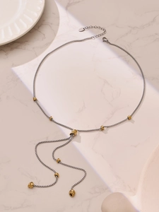 Gros plan sur le collier à perles bicolore en acier inoxydable sur fond de marbre