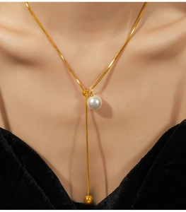 Detail einer eleganten Gold-Schlangenkette mit Perlenanhänger und verstellbarem Verschluss