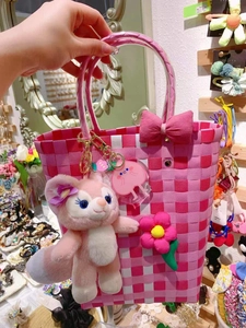 Detailed view of pink checkered woven handbag with floral bow and plush charm decoration