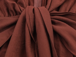 Detailed macro view of V-neck knot design and textured crepe fabric on a long sleeve dress