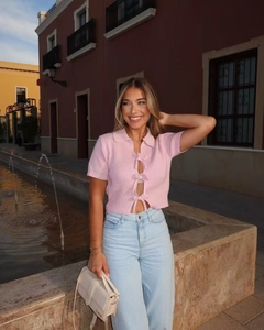 Close-up of pink short-sleeve knit top featuring three delicate bow tie closures