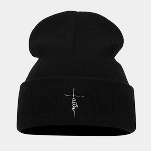 Close-up of black ribbed knit beanie featuring white faith cross embroidery detail