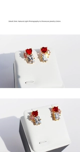 Detail shot of heart red zircon and emerald cut crystal stud earrings in gold finish