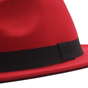 Detailed close-up of red wool felt fedora featuring a classic black grosgrain ribbon band