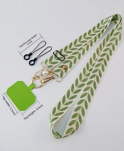 Detailed view of crossbody phone strap with green leaf pattern and pearl charm accessory