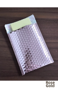 Detail of rose gold holographic bubble mailer showing self-seal strip and metallic texture