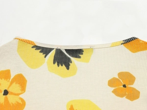 Close-up of ribbed crewneck neckline with yellow and orange floral print on cream top