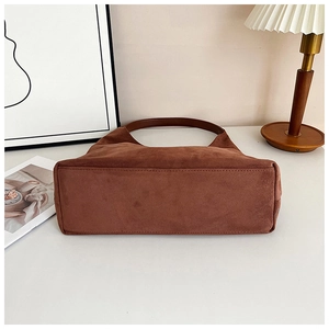 Close-up of brown suede tote bag in a stylish home interior with warm lighting