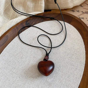 Detailed close-up of dark wood heart pendant on a display tray with natural linen textures