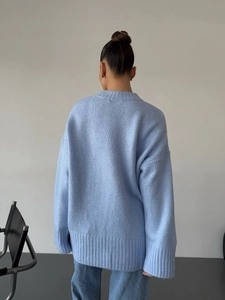 Detail of light blue oversized knit sweater showing loose fit and ribbed cuff texture