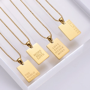 Detailed macro view of four gold rectangular pendant necklaces with motivational engravings