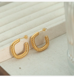Macro shot of gold twisted rope texture on geometric U-shaped chunky hoop earrings