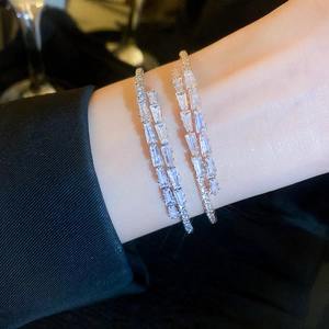 Detail of double-layer gold bangle set with sparkling rectangular and round zircons